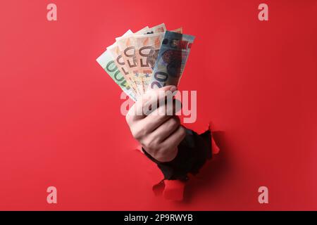 Businessman breaking through red paper with money in hand, closeup Stock Photo
