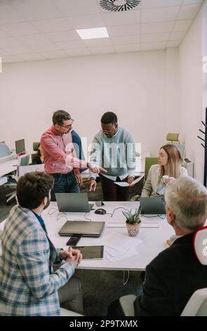 Five businesspeople discussing about their upcoming job at the office Stock Photo