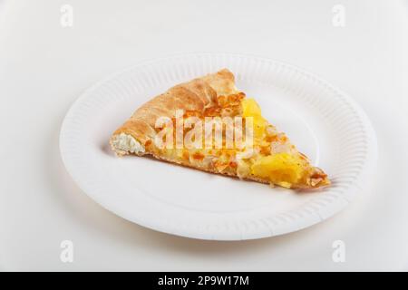 A piece of hawaiian pizza with chicken and pineapples with cheese board on paper dish isolated on white background. Stock Photo