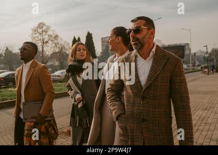 Tired businessman are walking next to their female colleagues while they are having a fun conversation Stock Photo