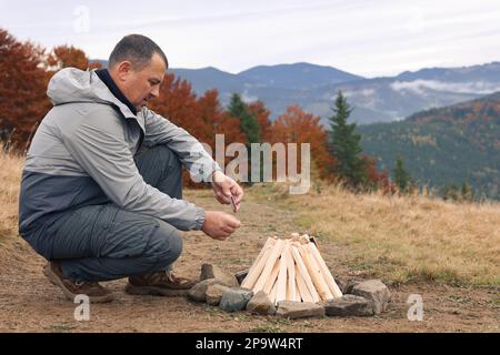 Man making bonfire in mountains. Camping season Stock Photo