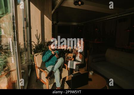Young, deaf business coworkers working remotely at the coffee bar. They are communicating using the sign language Stock Photo