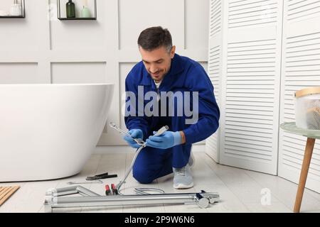 Professional plumber installing water tap in bathroom Stock Photo