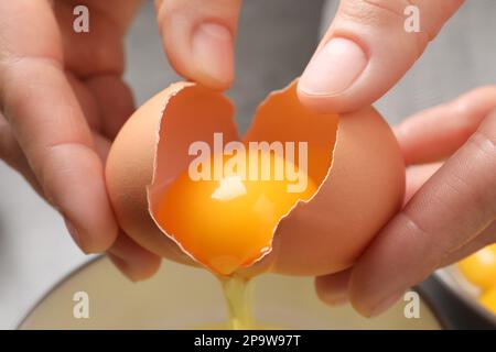 Woman separating egg yolk from white over bowl, closeup Stock Photo