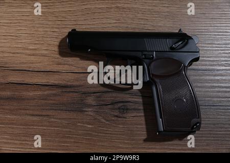 Handgun on wooden table, top view. Semi-automatic pistol Stock Photo