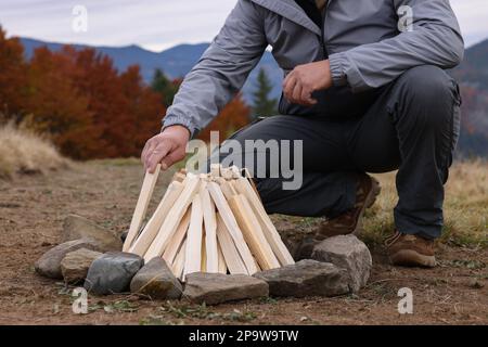 Man making bonfire in mountains, closeup. Camping season Stock Photo