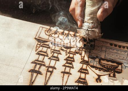 An artist using a pyrography tool to create a pyrogravure. Wood burning ...