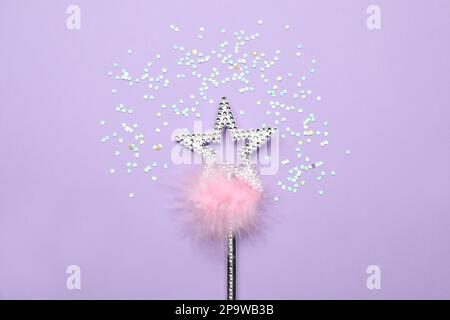 Beautiful silver magic wand with feather and confetti on lilac background, flat lay Stock Photo