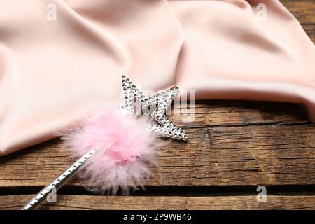 Beautiful silver magic wand with feather and pink fabric on wooden table, closeup Stock Photo