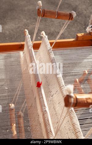 Detail of weaving equipment on the antique wooden loom and thread weaving shuttle. Handicraft textile cloth weave with traditional tools. Stock Photo