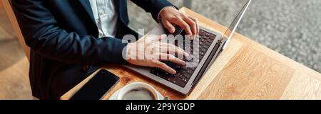 Close up of unrecognizable businessman working on laptop in coffee shop working space Stock Photo