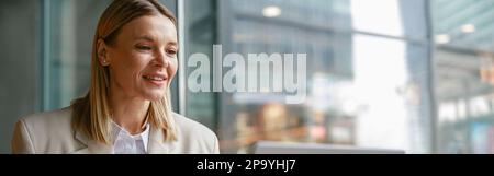 Happy businesswoman is having a business lunch and working on laptop in cafe. Blurred background Stock Photo