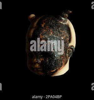 scary Isolated spooky possessed baby girl doll head creepy burnt face with gray eye on black background Close up macro Stock Photo