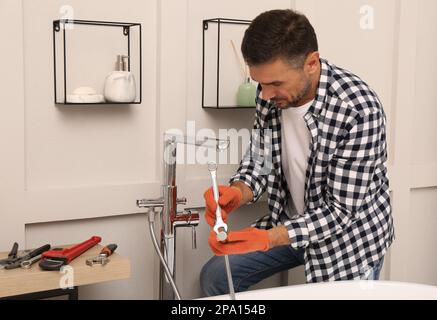 Man installing new water tap in bathroom Stock Photo