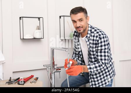 Man installing new water tap in bathroom Stock Photo