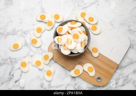 Delicious gummy fried eggs shaped candies on white marble table, flat lay Stock Photo