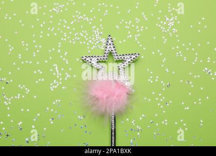 Beautiful silver magic wand with feather and confetti on light green background, flat lay Stock Photo