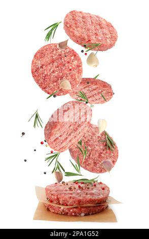 Fresh raw burger patties and seasonings falling on white background Stock Photo