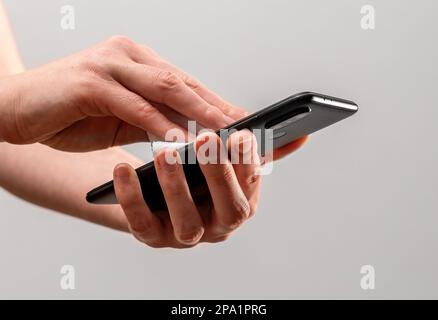 Hand wiping, cleaning phone screen with wet wiper. Stock Photo