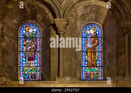 Two stained-glass windows with images of religious saints. The skylight architectural feature is seen from inside the Catholic church Stock Photo