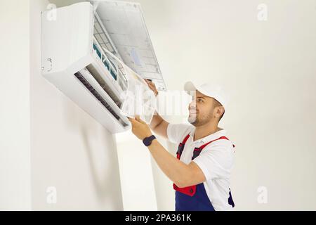 Portrait of smiling professional technician worker is changing filter in air conditioner indoors. Stock Photo