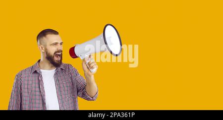 Young active man loudly announces crazy holiday discounts and sales using megaphone. Stock Photo