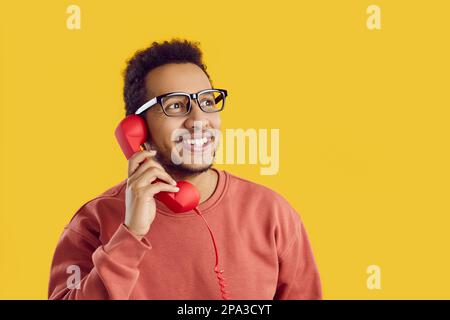 Happy young African American man talking to friends on landline phone and smiling Stock Photo