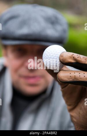 Elegant Golfer with Cap Holding a Golf Ball in Switzerland. Stock Photo