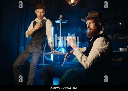 Serious guys smoking hookah while rest in the pub Stock Photo