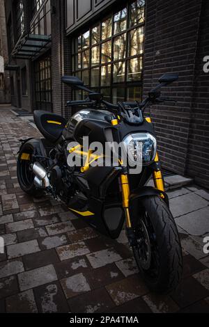 a black and yellow motorcycle is parked on the street. Stock Photo