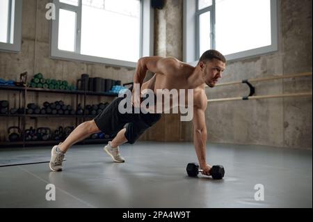 Handsome muscular man doing push ups or standing in wide plank on one arm Stock Photo
