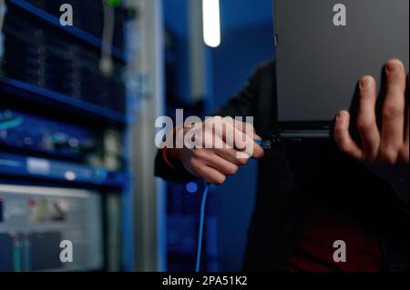 IT technician switching wire to laptop computer closeup Stock Photo