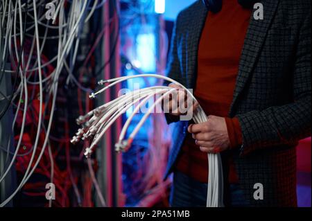 IT man with bunch of cables in hands in server room Stock Photo