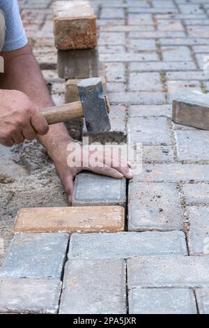 Brazilian and construction worker tapping a small mallet on the concrete block vertical. Stock Photo