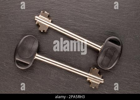 Two metal keys from a door lock on slate stone, macro, top view. Stock Photo