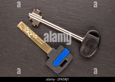 Two metal keys from a door lock on slate stone, macro, top view. Stock Photo