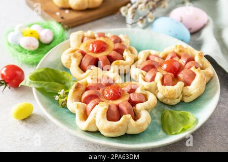 Idea for Easter breakfast or lunch. Mini pizza. Pizza in puff pastry with cheese and tomatoes on the festive table. Stock Photo