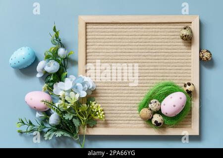 Springtime welcome concept. Letter board, Easter eggs and spring flowers on a pastel blue background, minimalism style composition. View from above. Stock Photo