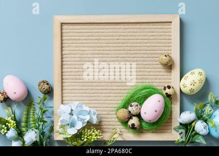 Letter board, Easter eggs and spring flowers on a pastel blue background. Springtime welcome concept. Stock Photo