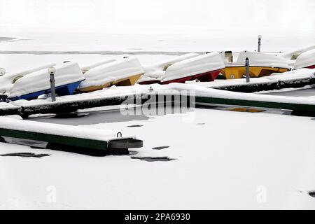 Winter landscape with many overturned boats covered with snow on a dock on a frozen river in no season Stock Photo