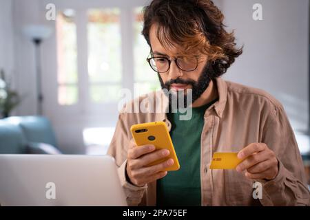 Man shopping online paying using credit card and smartphone from home. Stock Photo