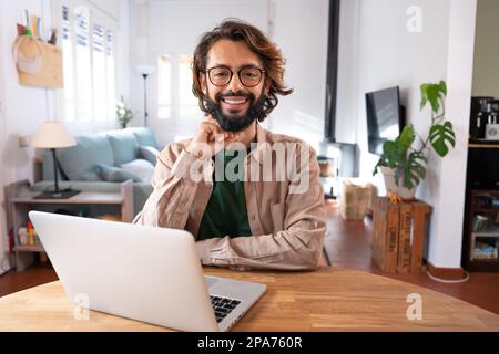 Cheerful smiling male looking at camera using laptop at home remote work in a small business. Stock Photo