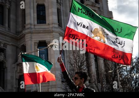 Madrid, Spain. 11th Mar, 2023. A woman waving an Iranian flag with the words 'Woman, life, freedom' during a protest where the Iranian community in Madrid are demonstrating against the hundreds of young girls poisoned in Iran in a suspected attempt to close schools since past November. Credit: Marcos del Mazo/Alamy Live News Stock Photo