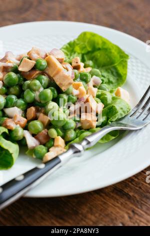 Pea salad with non-dairy cheese and vegan sausage pieces. Stock Photo