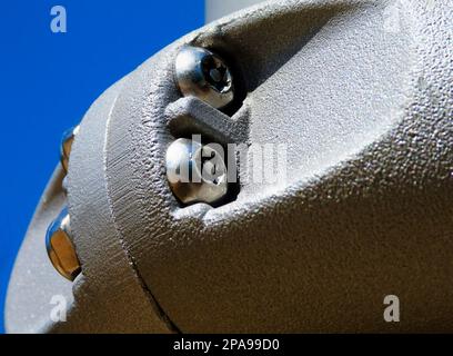 Torx or star head stainless steel screw macro view. coupling of light gray color power coated metal fastening clamps. bright light and clear blue sky Stock Photo