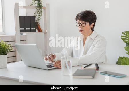Businesswoman working in office doing video call with laptop. Female professional making videocall Stock Photo