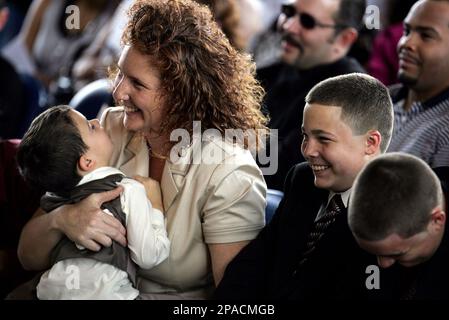 Widow Michele Vazquez holds her son Adrian 4 while sitting with