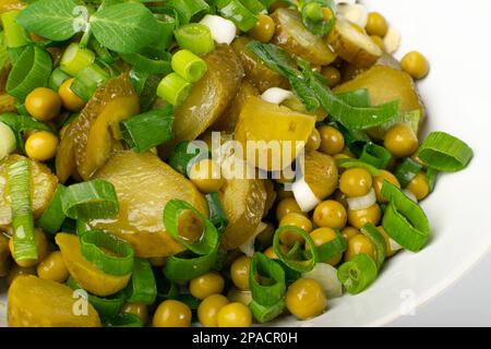 Pickled Gherkins Salad in White Bowl. Chopped Pickled Cucumbers, Canned Green Peas, Green Onions Salat Isolated on White Background Stock Photo