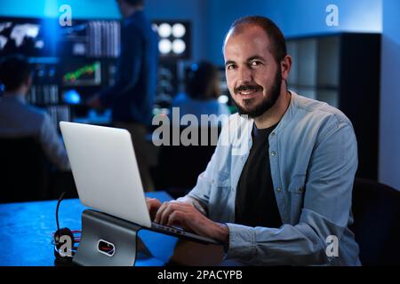 Smiling Portrait looking camera of a happy Financial Analyst Working on a Computer with Multi-Monitor Workstation Stocks. Businessman Works in Stock Photo