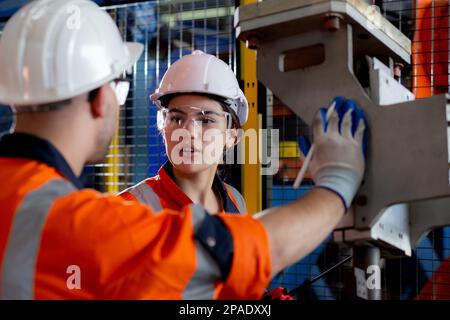 Young engineer man and woman talking and explaining about robot arms technology intelligence and innovation at factory, development machine, people me Stock Photo